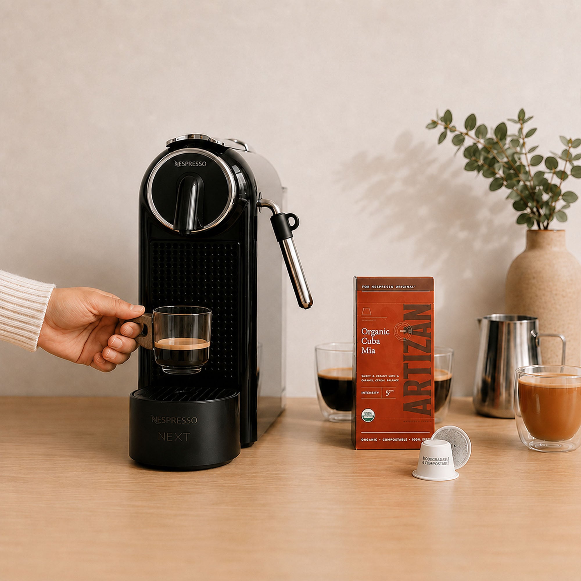 Small glass espresso cup with wooden handle held beneath a coffee machine in a minimalist home coffee station.