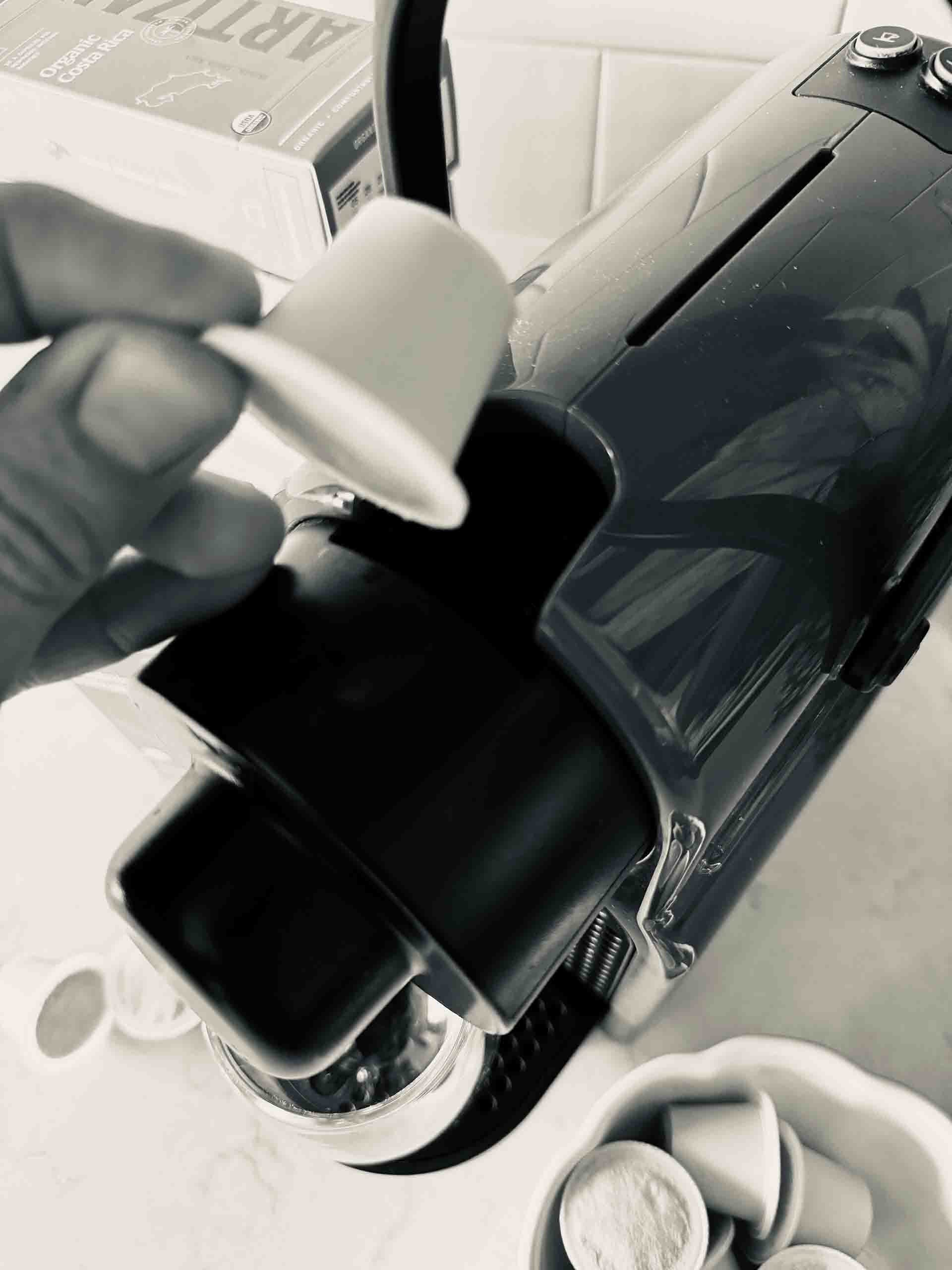 Image of an organic compostable Nespresso Original capsule being inserted into an Inissia Original coffee machine.