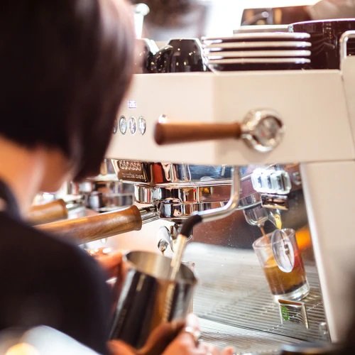 Barista using the White Variant Ascaso Barista T Plus Automatic 2 Group Espresso Machine