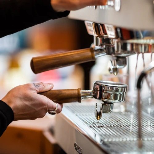 Angled view of Ascaso Barista T Plus Automatic 3 Group Espresso Machine with three stainless steel group heads, digital PID displays above each group, steam wands on both sides, and a polished drip tray.