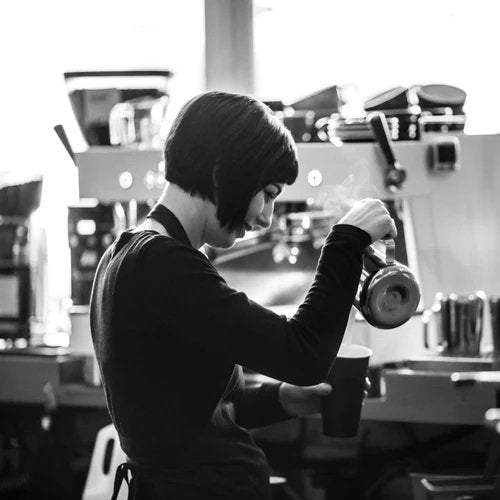 Barista pouring coffee on cup after using Ascaso Barista T Plus Automatic 3 Group Espresso Machine