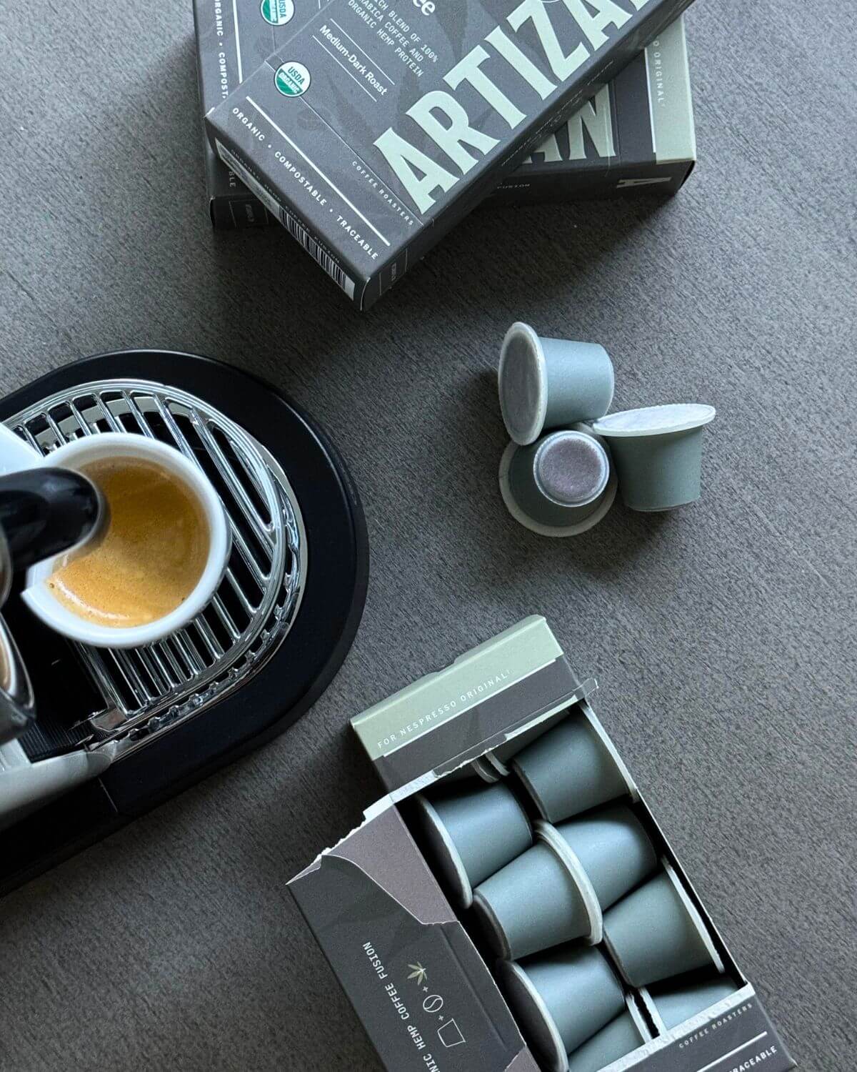 Artiza coffee capsules with a coffee machine and open box on a gray surface