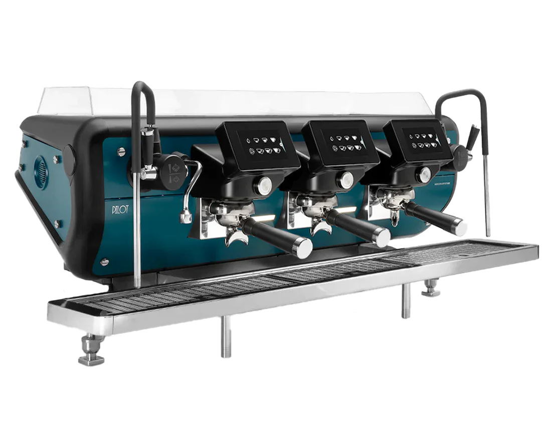 A three-group Barista Attitude Pilot commercial espresso machine in a Pilot blue and black finish is shown in the image. This machine is the brand's first single-boiler model, featuring independent 5-inch touch displays on each group head, cool-touch steam wands with ergonomic levers, and an adjustable drip tray.