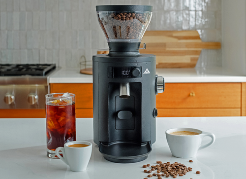 Mahlkönig coffee grinder with espresso, cappuccino, and cold brew drinks on a kitchen counter.