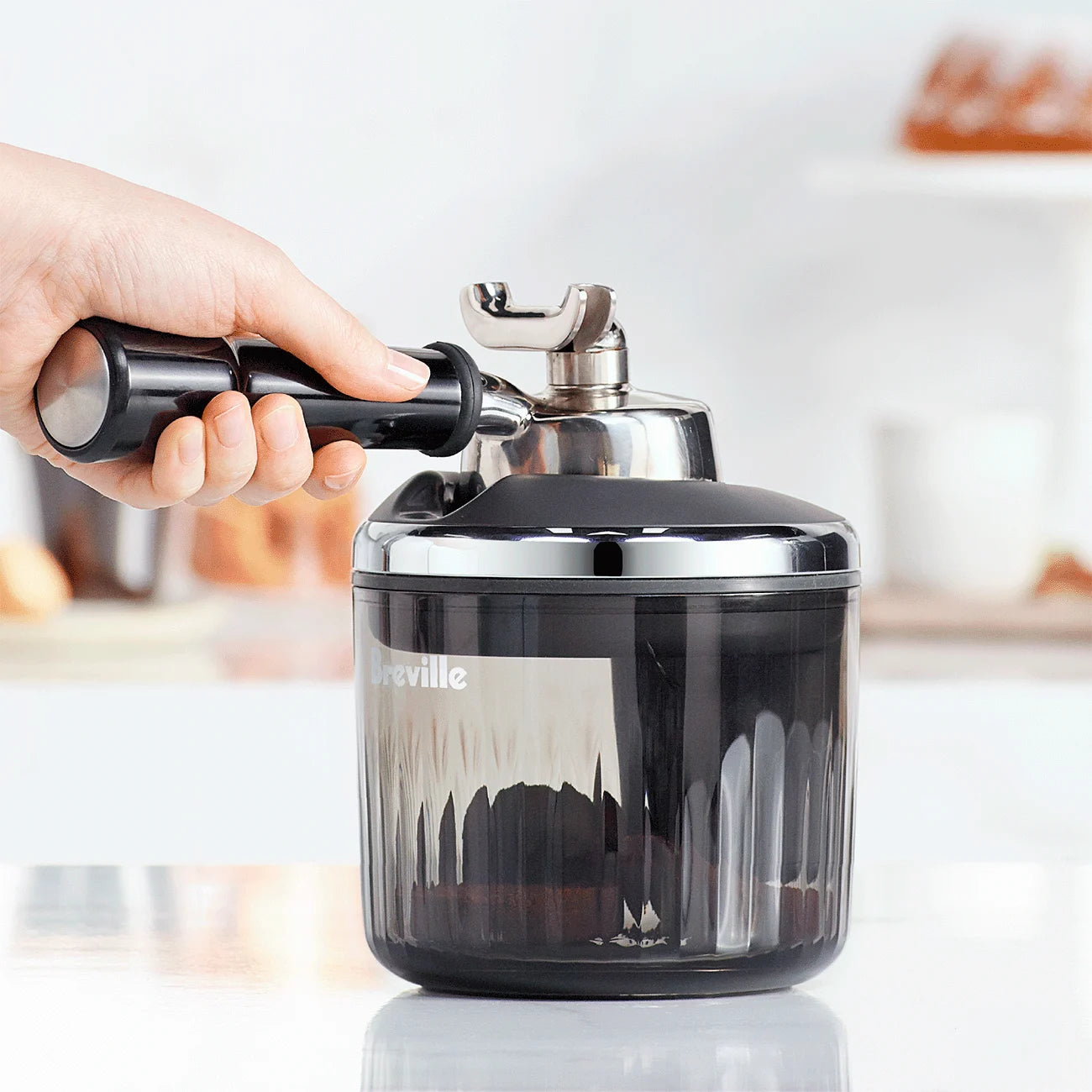 Close-up of The Puck Suker suction tool attached to a portafilter basket, removing used espresso puck effortlessly