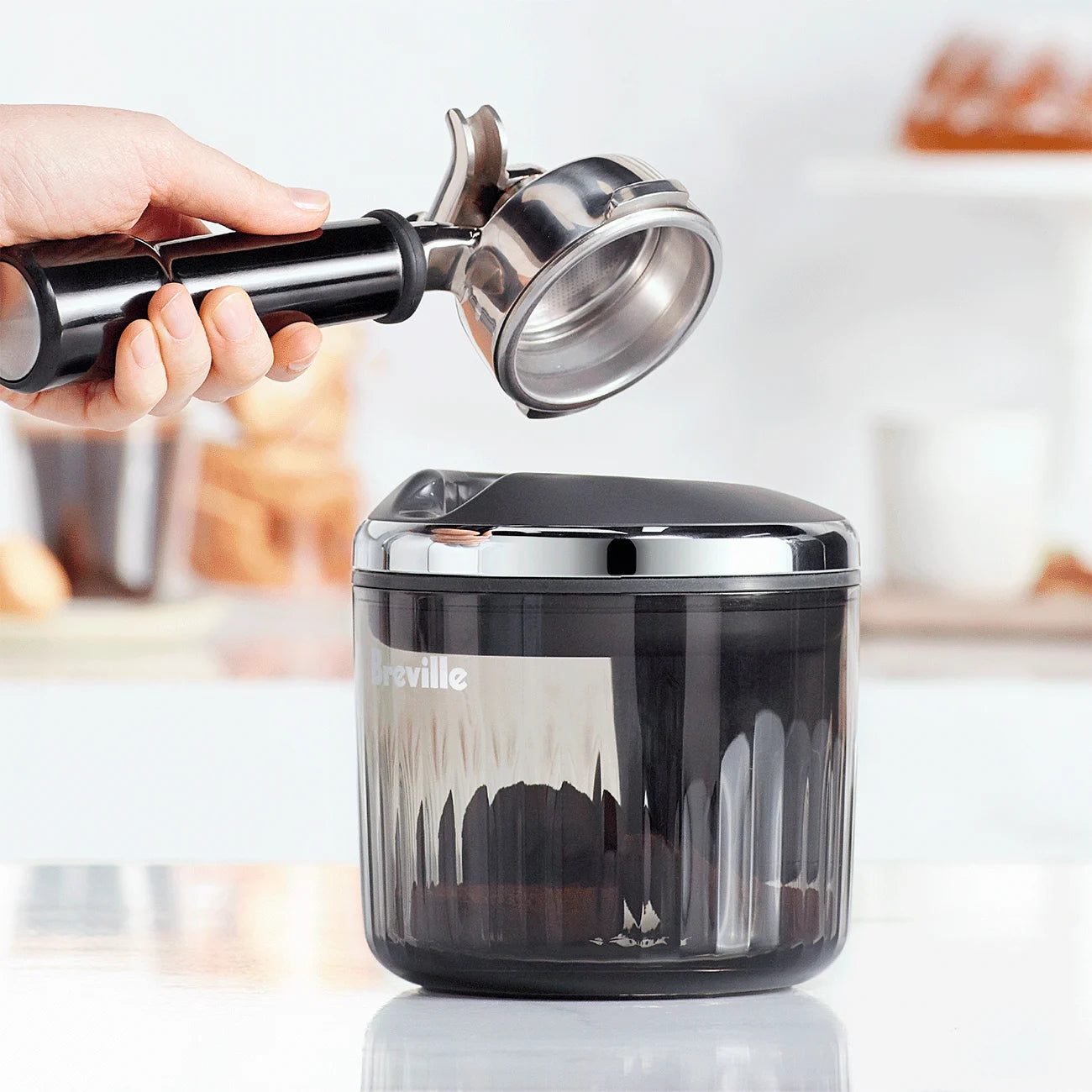Barista using The Puck Suker to lift spent espresso puck from portafilter, demonstrating hands-free clean removal