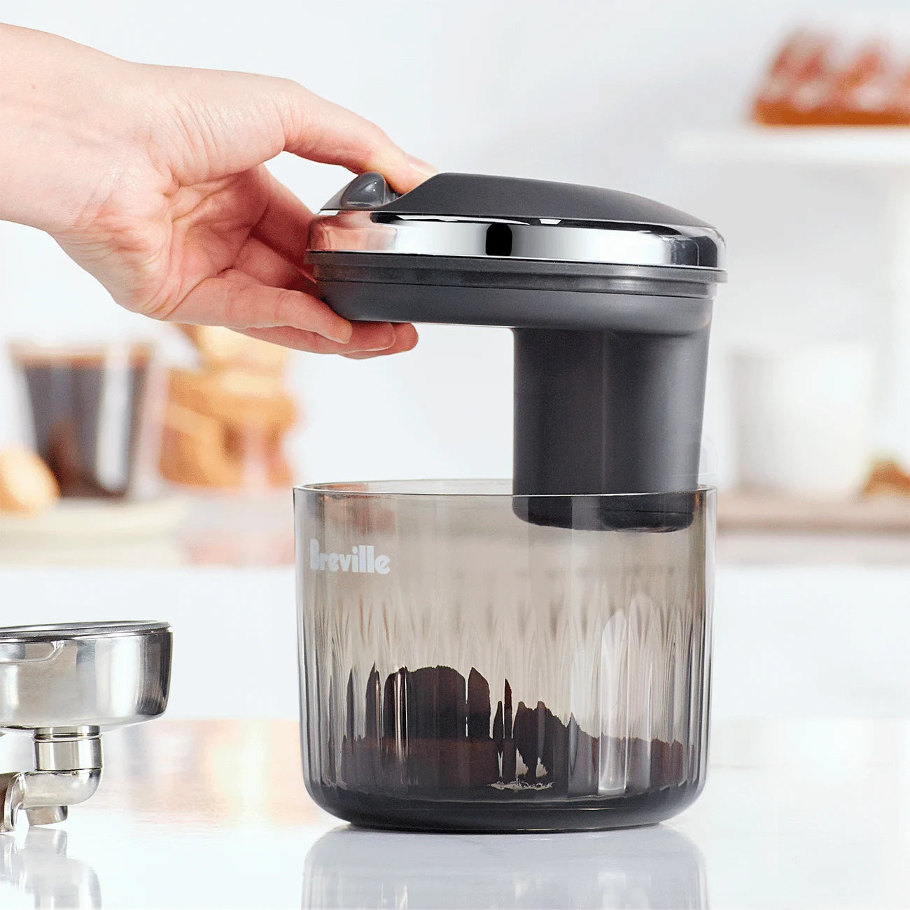 The Puck Suker espresso puck remover placed on a counter beside portafilter and coffee tools