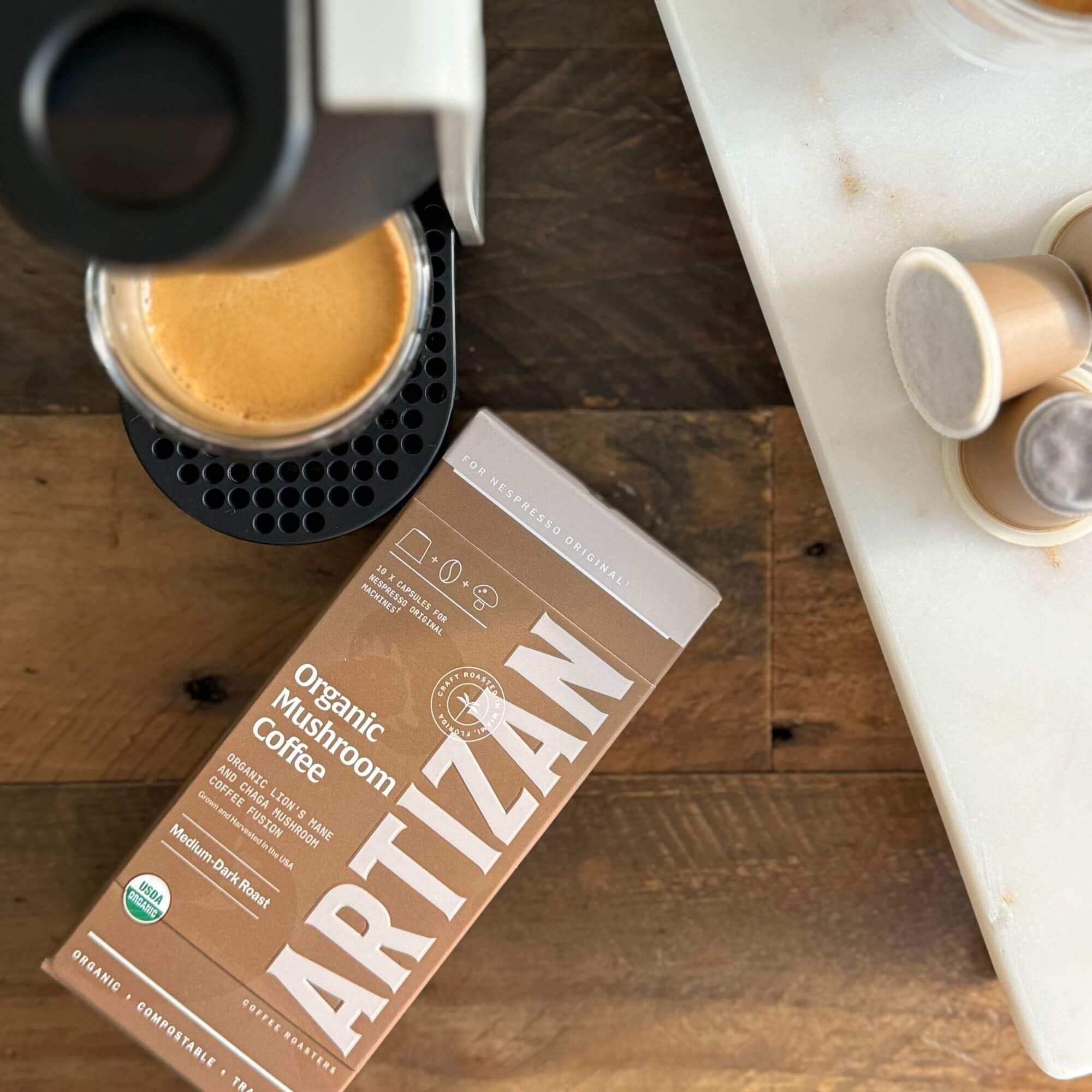 Artizan Organic Mushroom Coffee Nespresso pods with brewed espresso on wooden counter