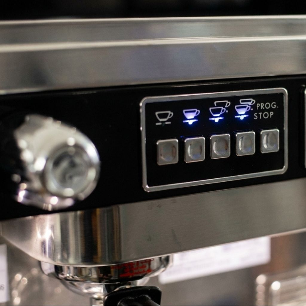 Astoria espresso machine brewing espresso into ceramic coffee cups with illuminated control panel.