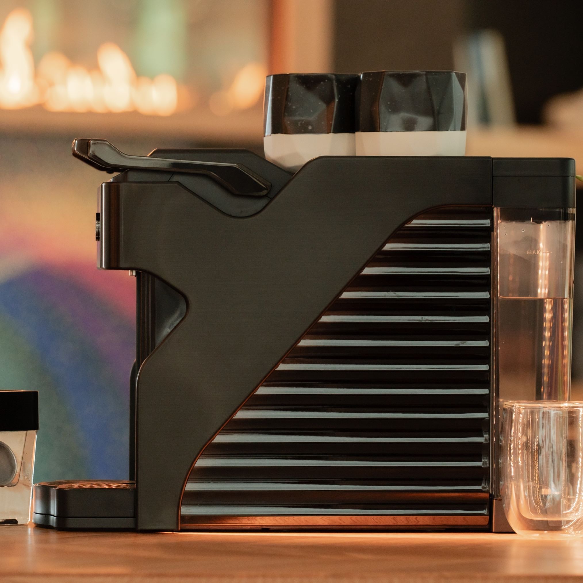 Side profile of Line1 Espresso and Coffee Machine in Brushed Nickel and Onyx with colorful ambient background
