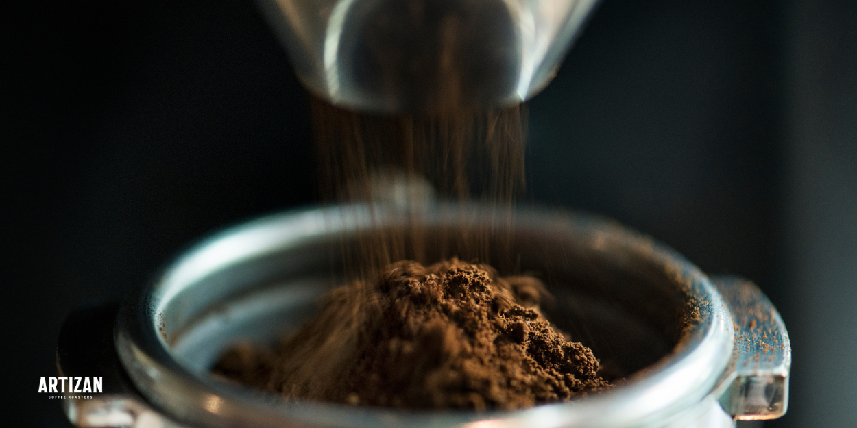 Freshly ground coffee beans falling into a portafilter for espresso, highlighting the quality and freshness of Artizan Coffee Roasters.