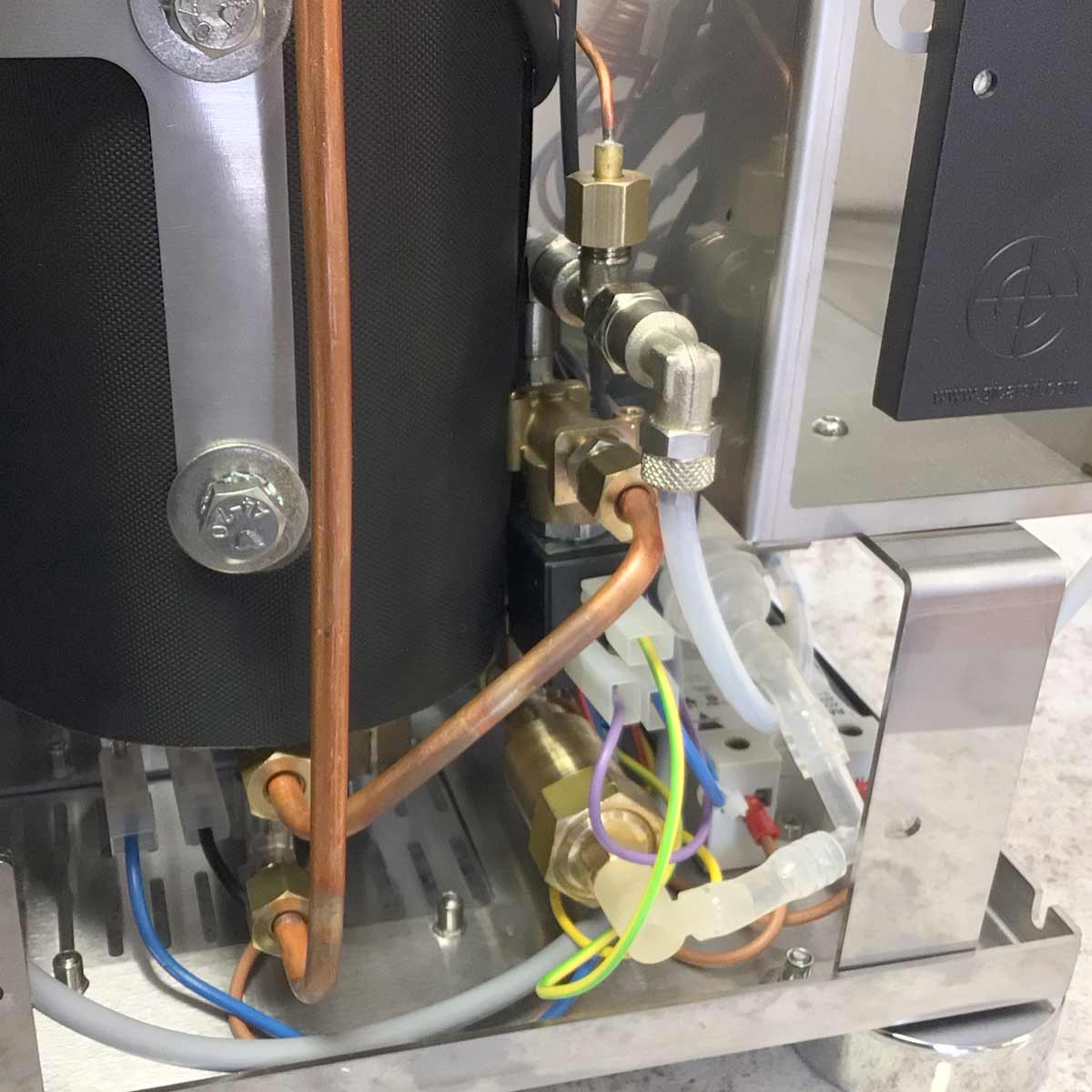Close-up of Torre Luigino HX espresso machine with flow control, copper pipes, wiring, and internal components.