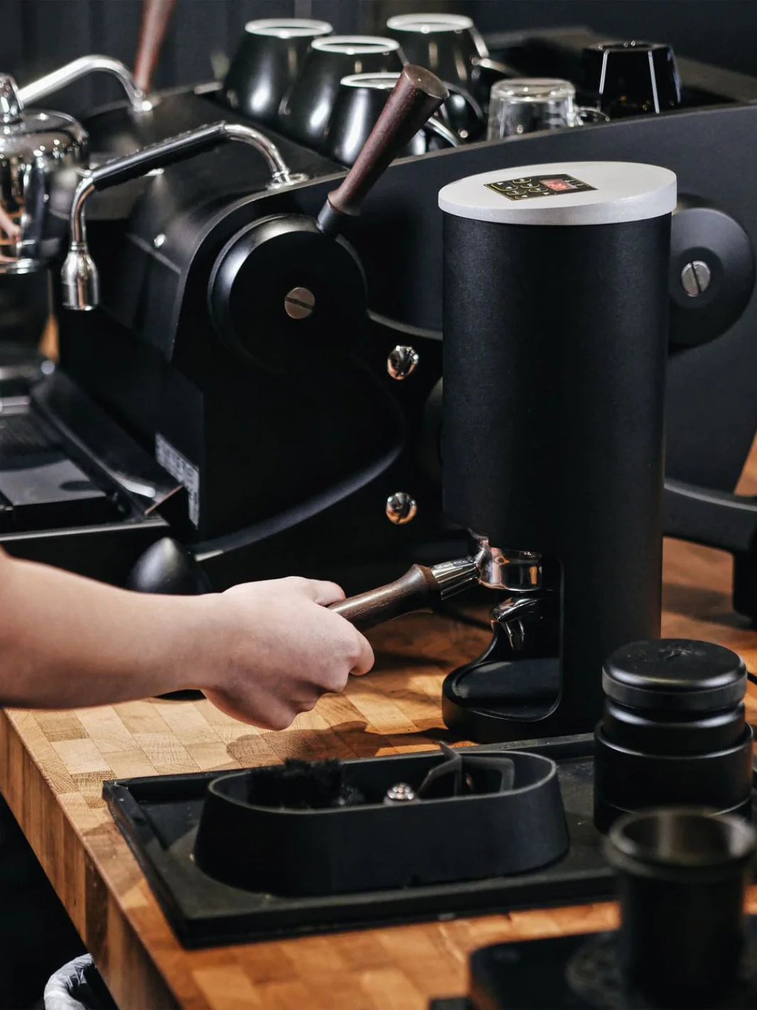 PT2 automatic coffee tamper in black placed on a professional coffee bar setup