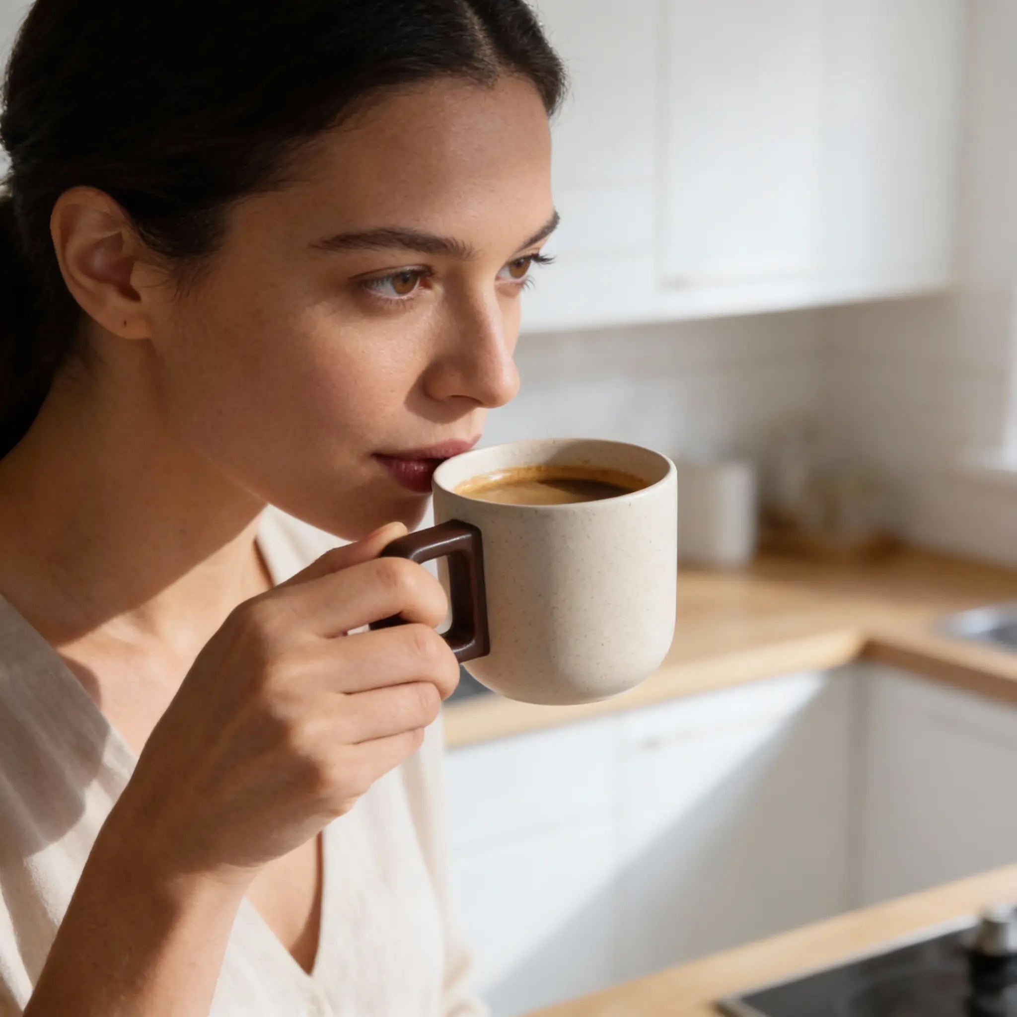 Modern beige ceramic coffee mug with a brown handle, perfect for enjoying hot beverages.