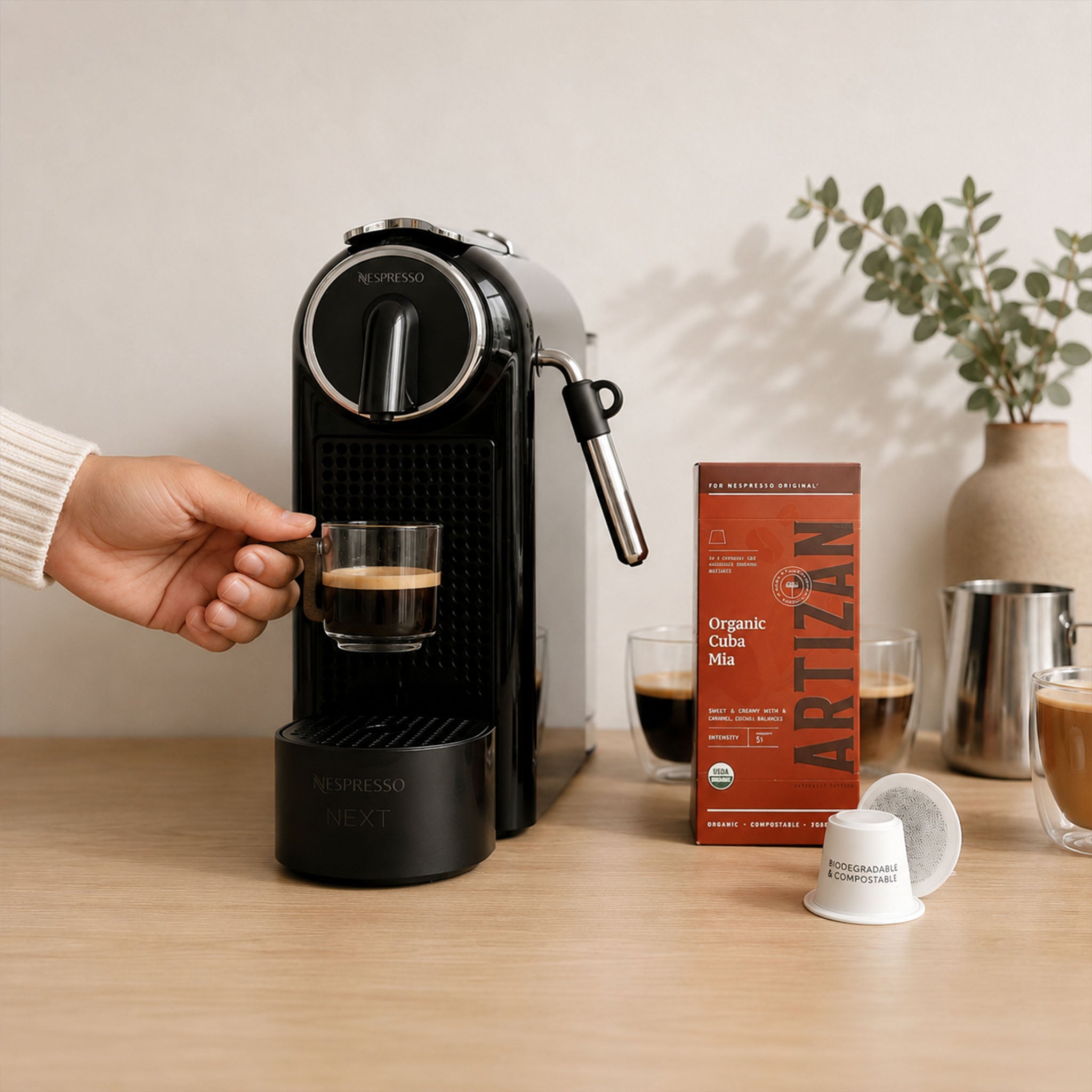 Small glass espresso cup with wooden handle held beneath a coffee machine in a minimalist home coffee station.